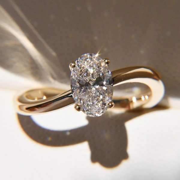 Un diamante oval, brillante como un latido eterno, se entrelaza con un cuerpo infinito que susur